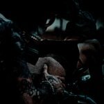 A dimly lit scene capturing the intense focus of a tattoo artist at work, their hands adorned with intricate ink designs, skillfully etching a new masterpiece.