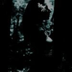 Silhouette of a serene woman with a flower in her hair against a dappled light background.