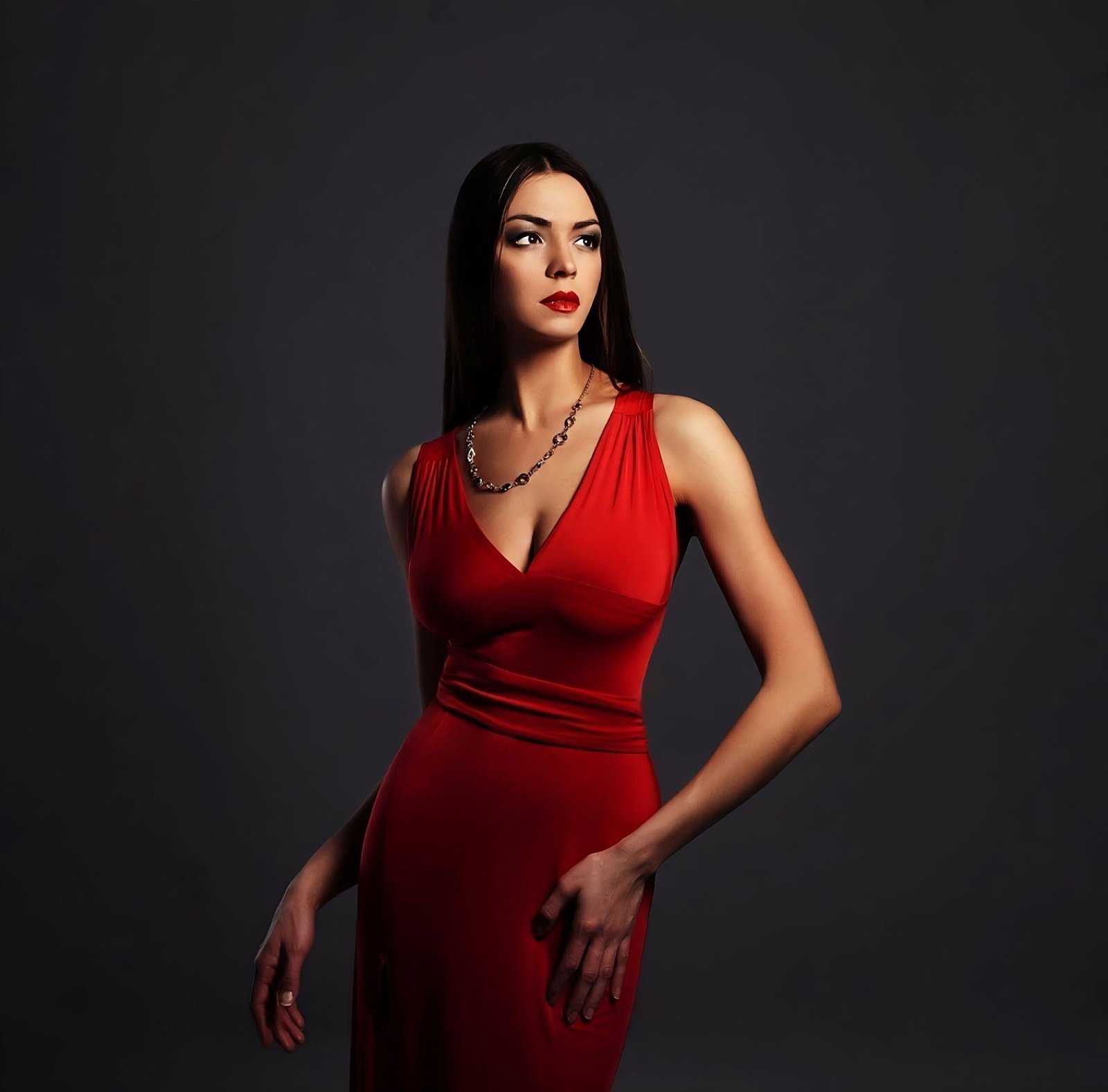 Elegant woman in a form-fitting red dress, posing against a dark background with a captivating expression.