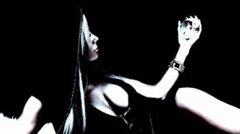 Woman reclining in a dark dress, holding a crystal sphere, with a focused expression against a stark black background.