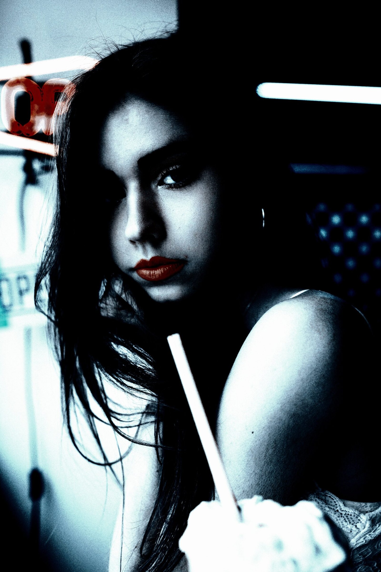 Alternative Goth and Metalhead Fashion: A woman with red lipstick sipping a milkshake in a blue-toned, moody setting, reflecting a casual goth style.