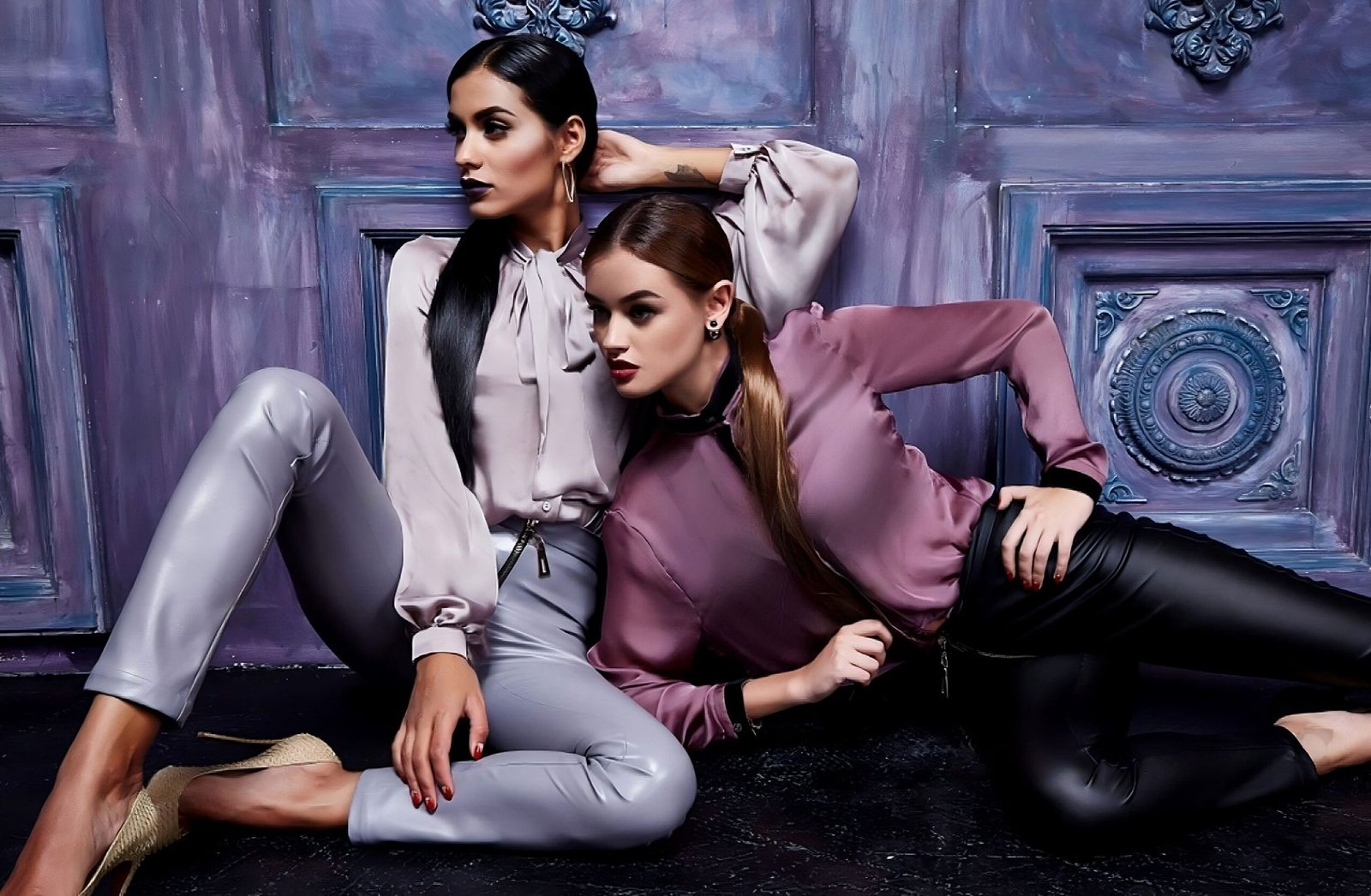Two fashion-forward professionals in contrasting silk blouses and metallic pants, redefining teamwork with style.