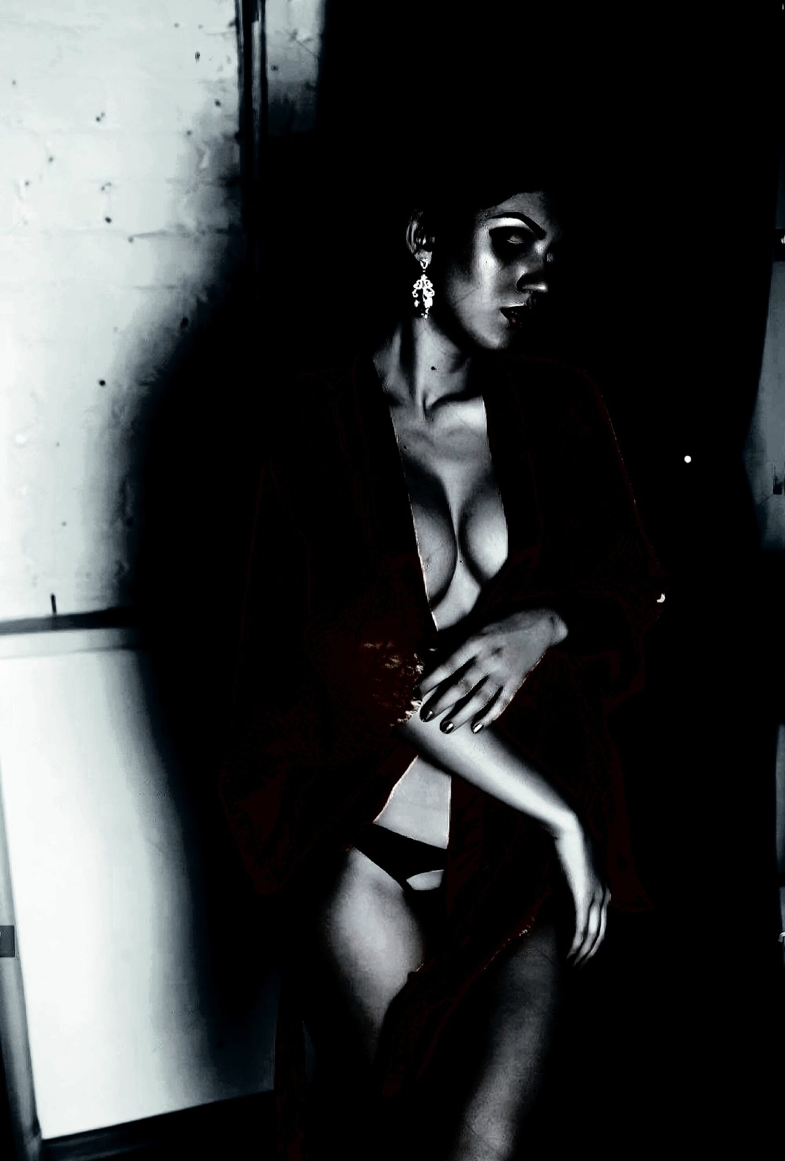 Figure in a dark, textured setting conveying gender fluidity with an intense, contemplative gaze.