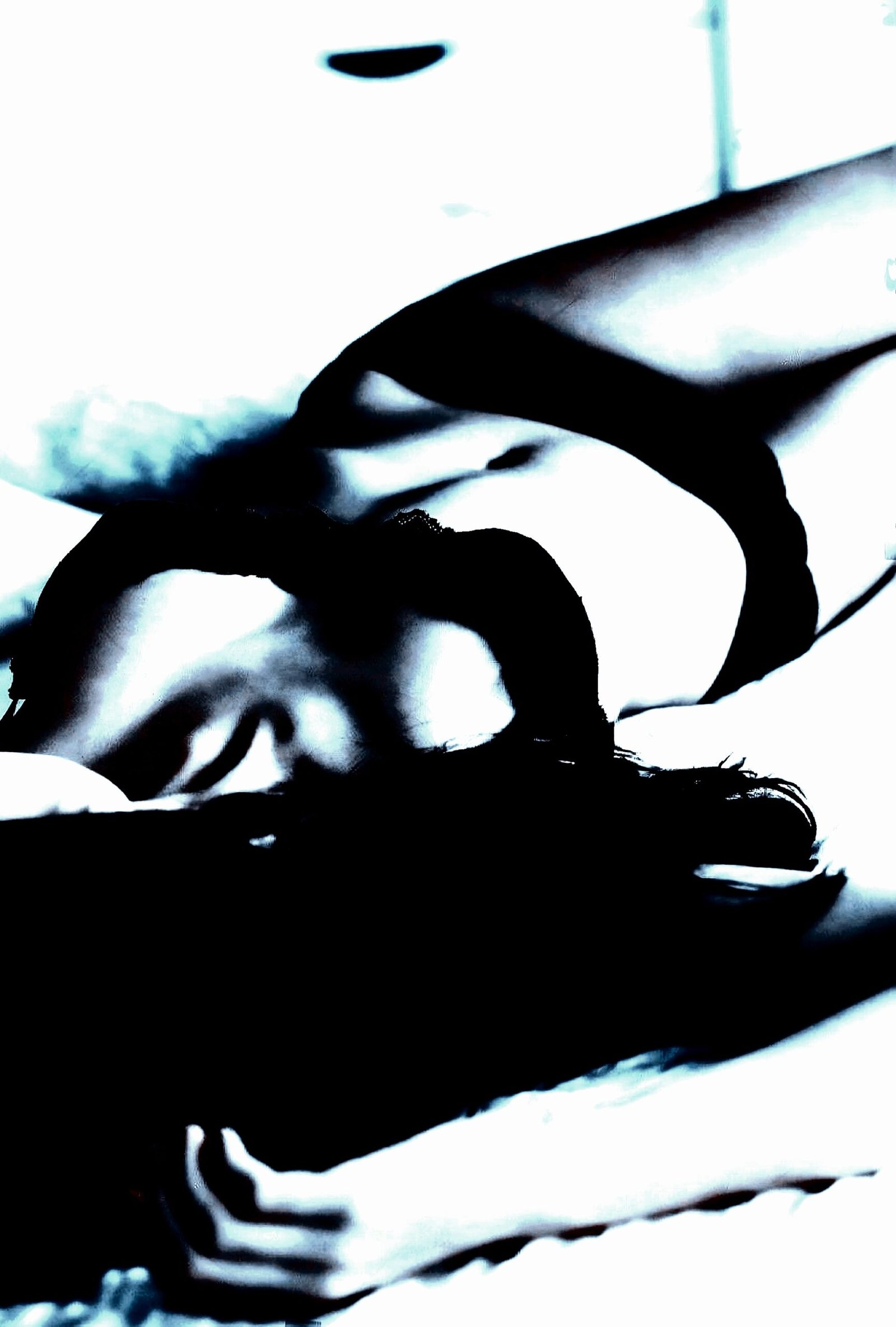 Contorted figure in repose, creating a striking visual narrative of gender fluidity in shadow play.