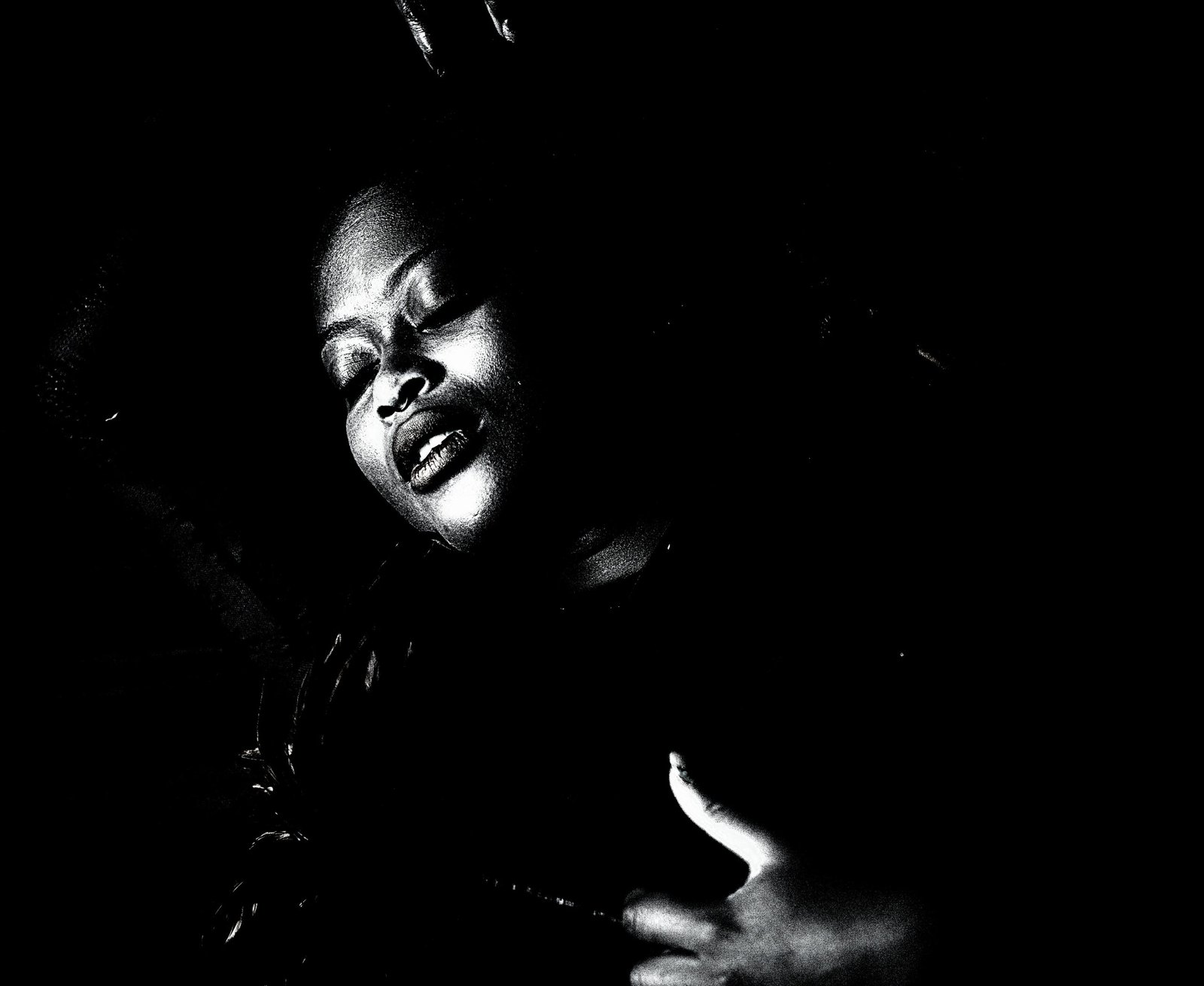 An artistic monochrome portrayal of a person's face in partial shadow, with an expression of serene submission, reflecting the intensity of the moment.