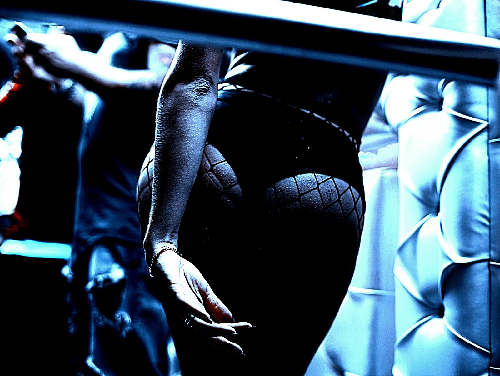 Close-up of a woman's fishnet-clad legs with a blue, moody gothic ambiance.