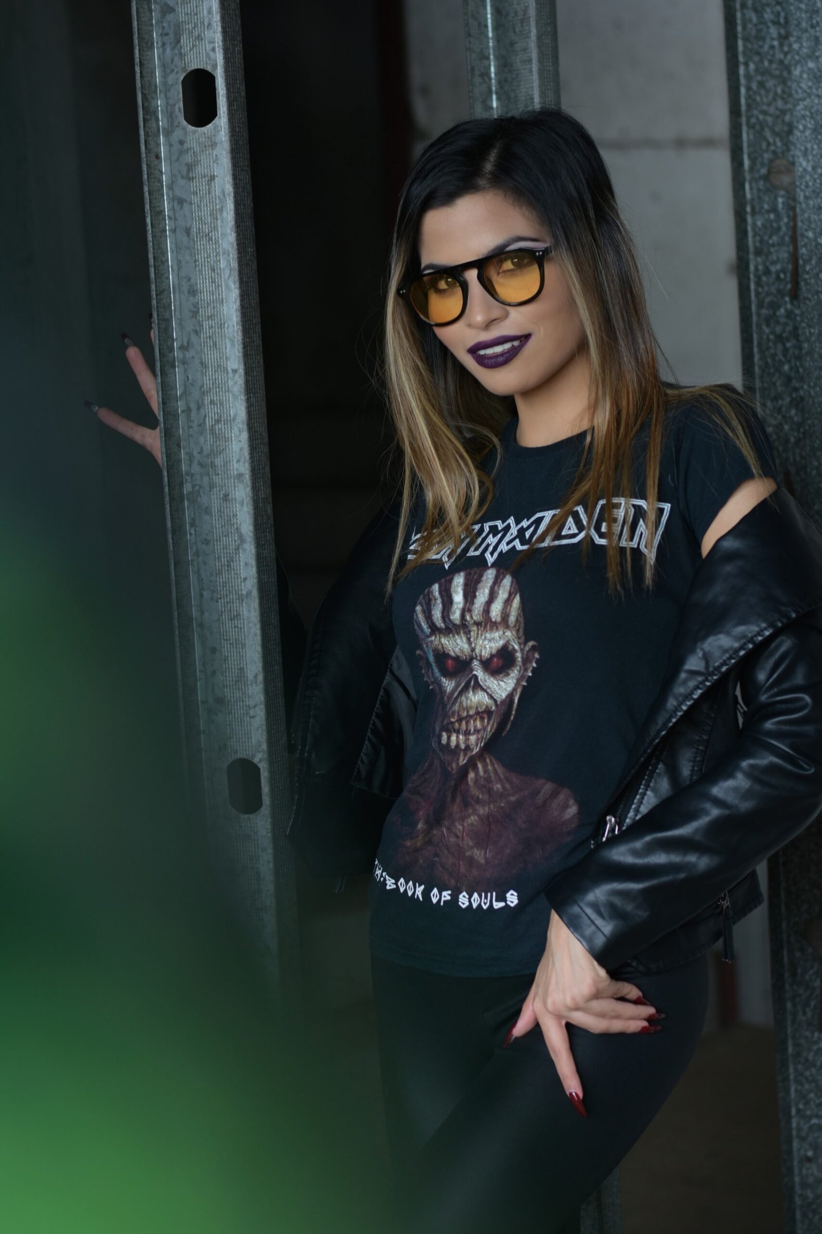Confident woman showcasing Victorian grandeur meets modern edge in Iron Maiden band tee and black leather jacket.