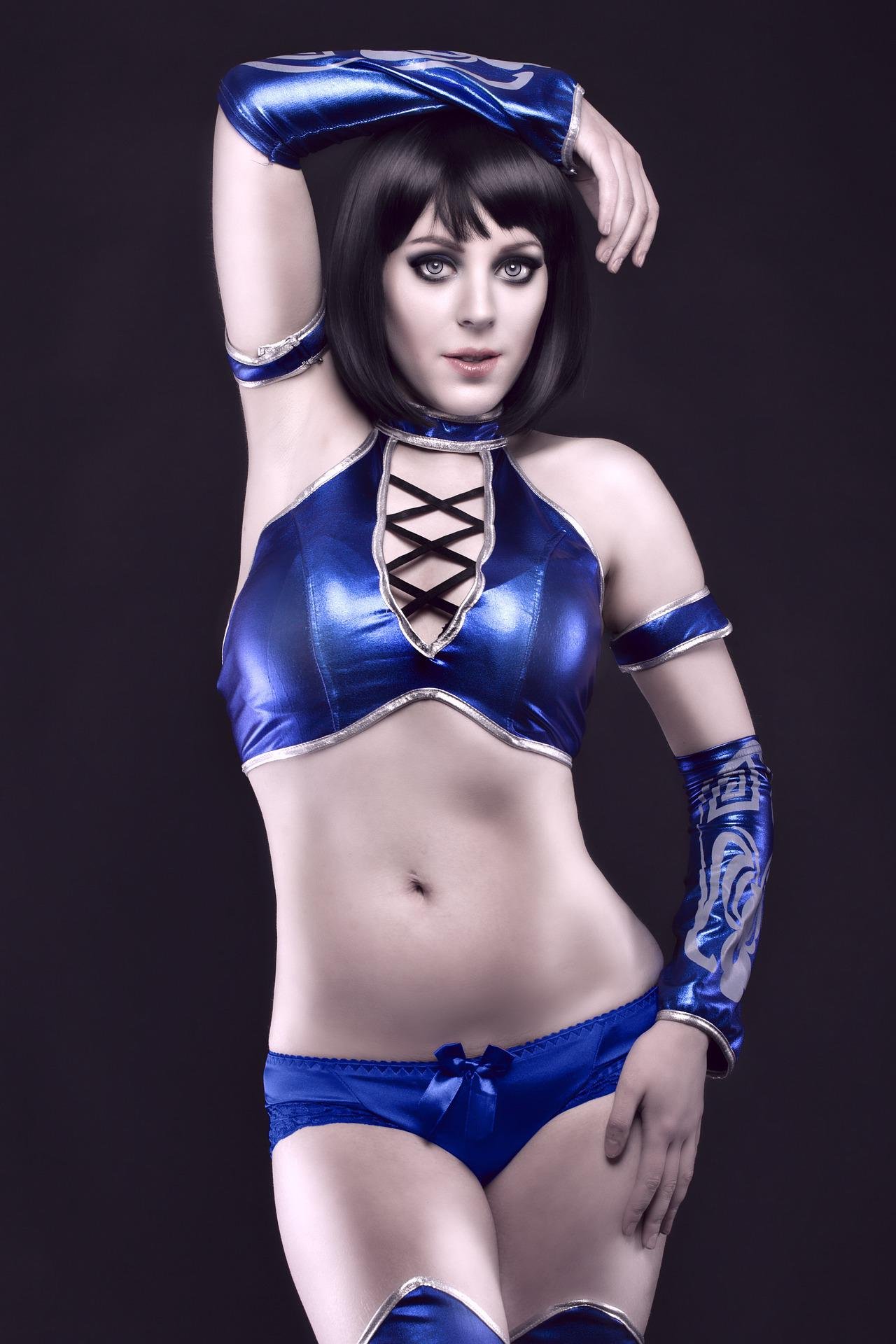 Portrait of a cosplayer in a shiny blue costume with arm sleeves and a confident pose.