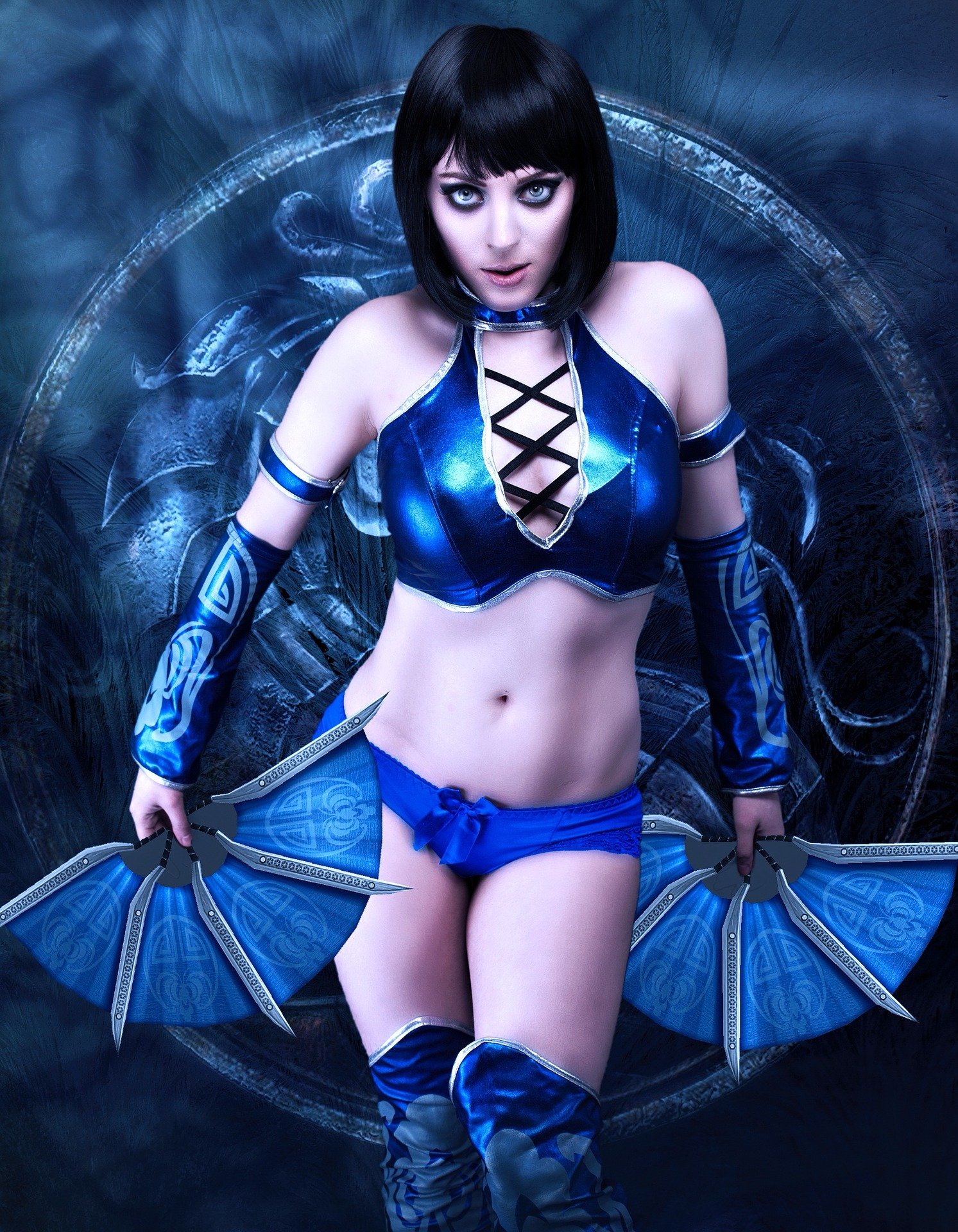 Cosplayer in a blue warrior-inspired outfit with intricate arm tattoos and fan blades.