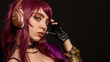 Cosplayer with purple hair and headphones, wearing a vibrant purple jacket and a choker.