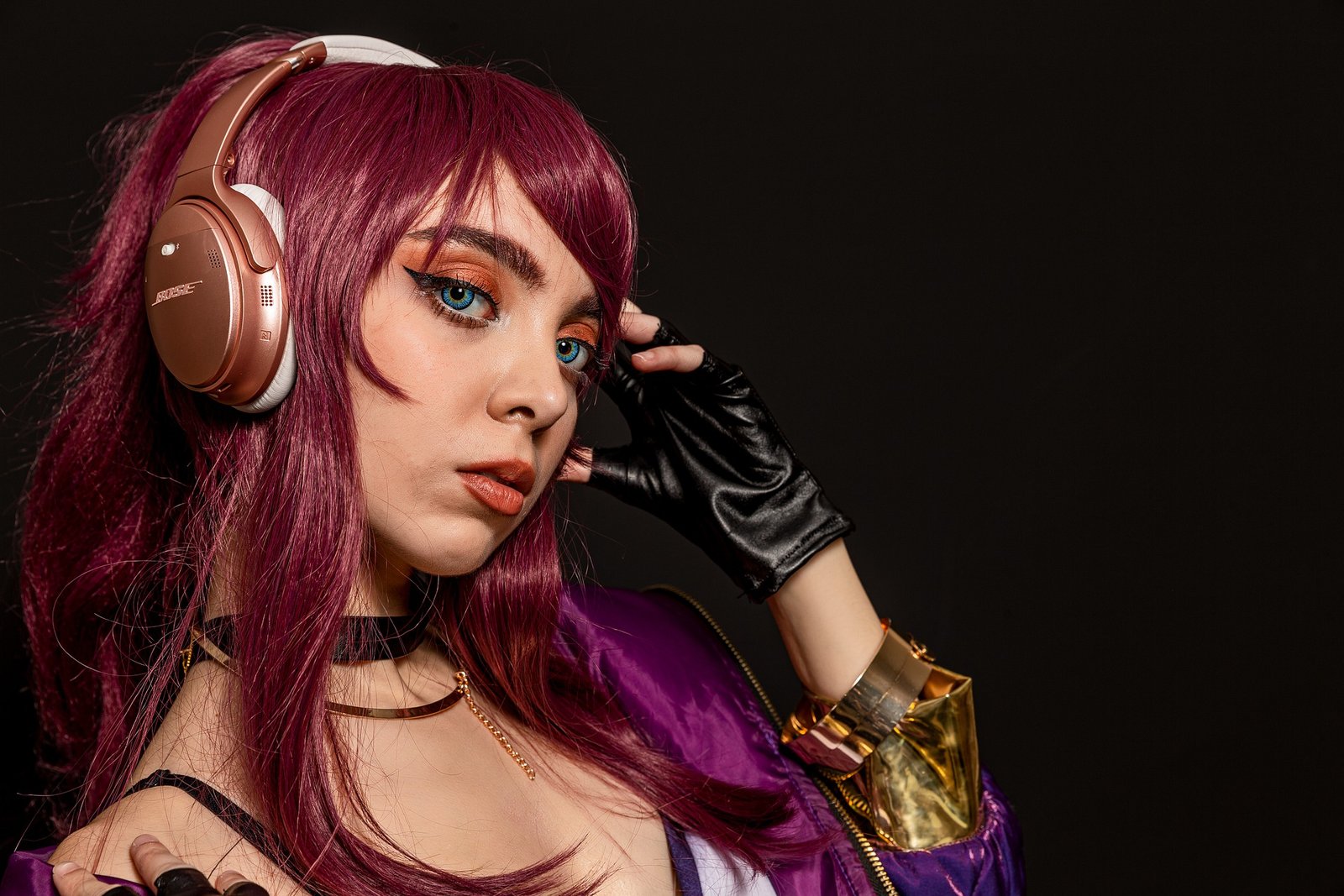 Cosplayer with purple hair and headphones, wearing a vibrant purple jacket and a choker.