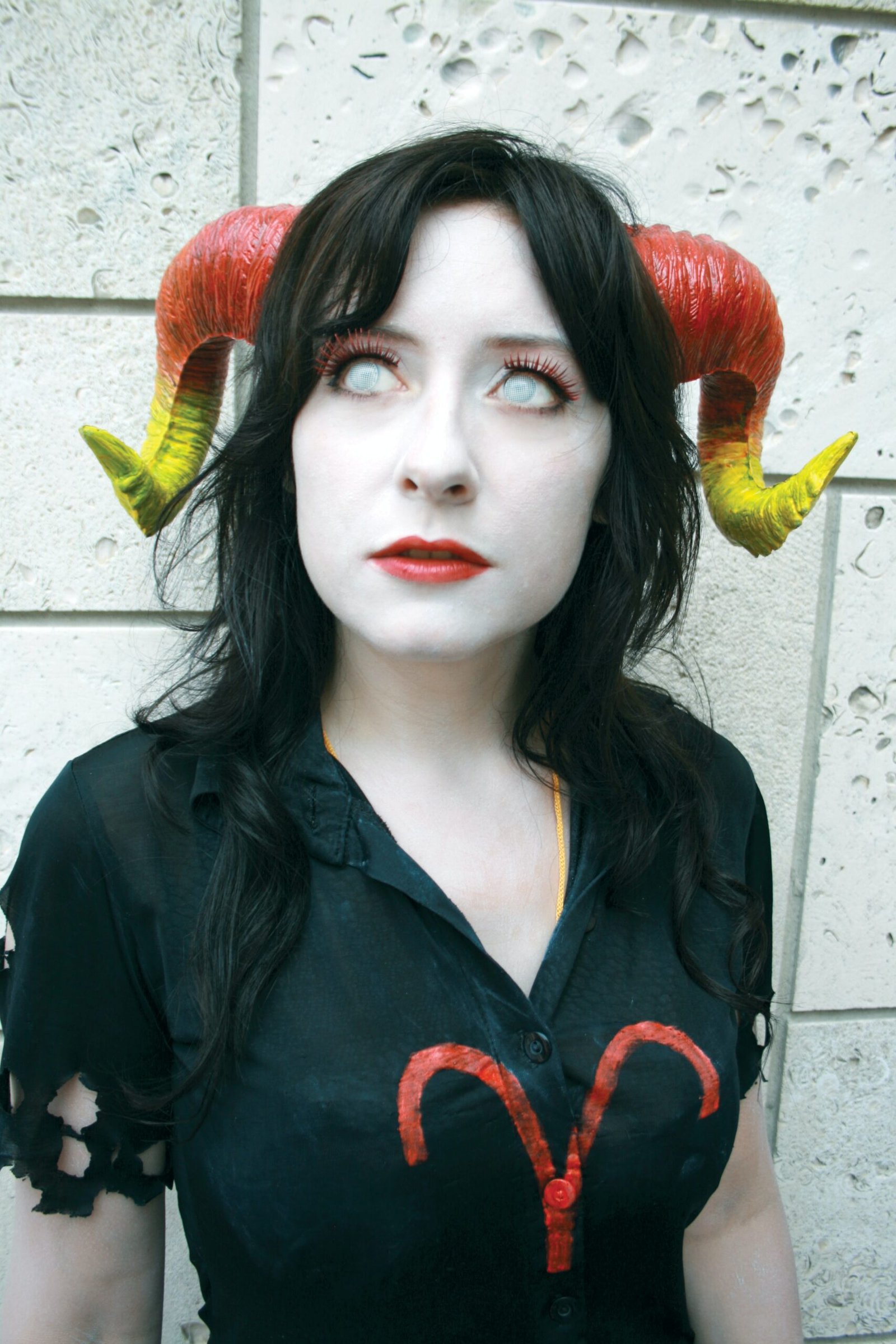 Gothic cosplay with large curved horns and a tattered black shirt, embodying a dark fantasy character.