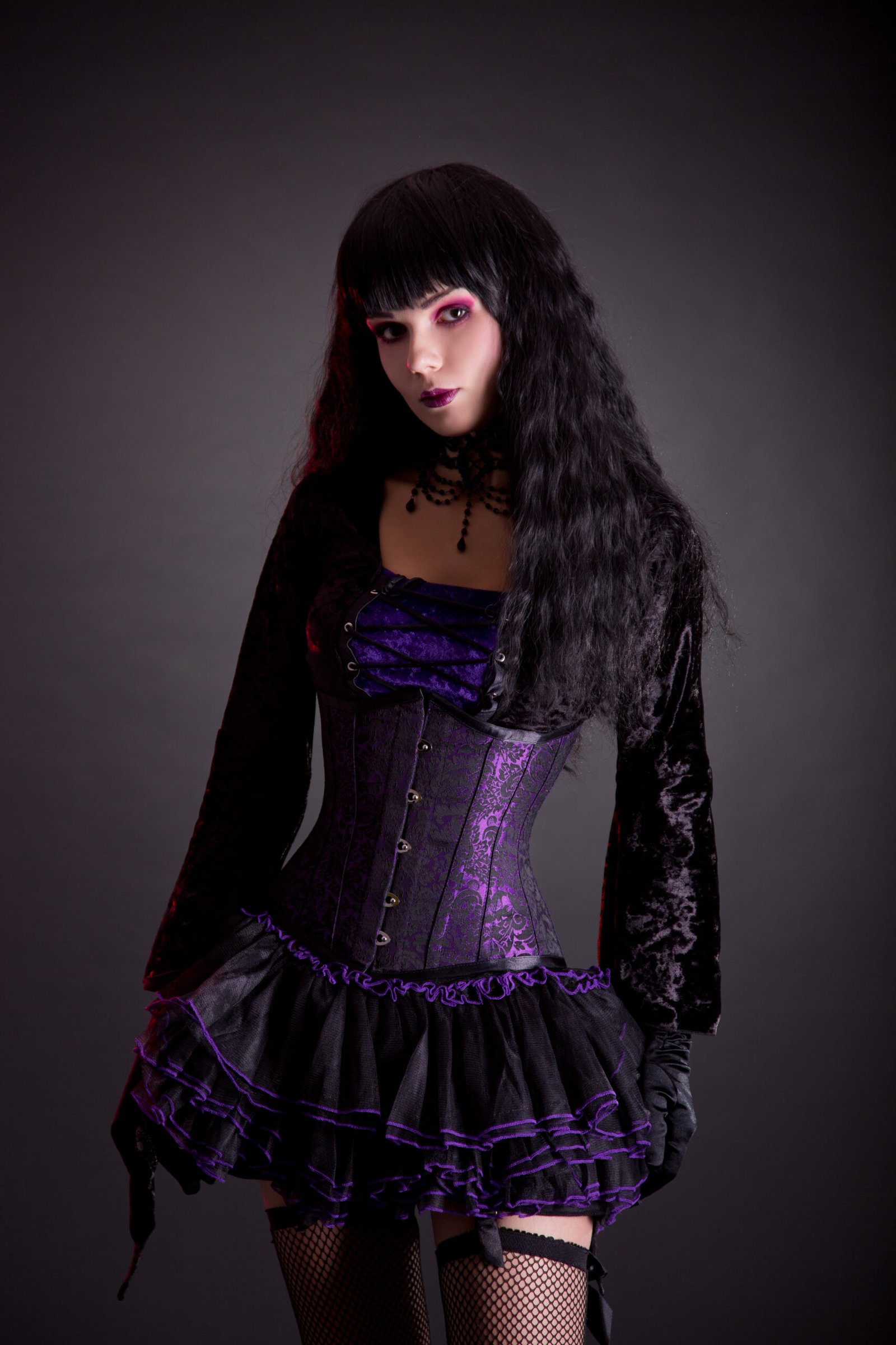 A woman channels her inner goth queen in a velvet corset dress with elegant lace sleeves and choker.