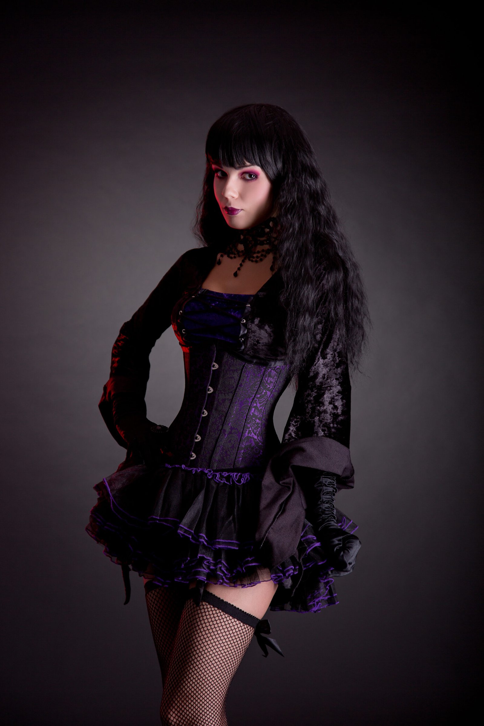 Portrait of the goth woman in a dynamic pose, her jacket flowing behind her, revealing the full splendor of her outfit's details and her commanding presence.