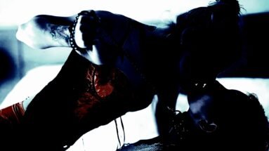An intense scene showing two women engaging in a passionate embrace, with a dark and moody backdrop.