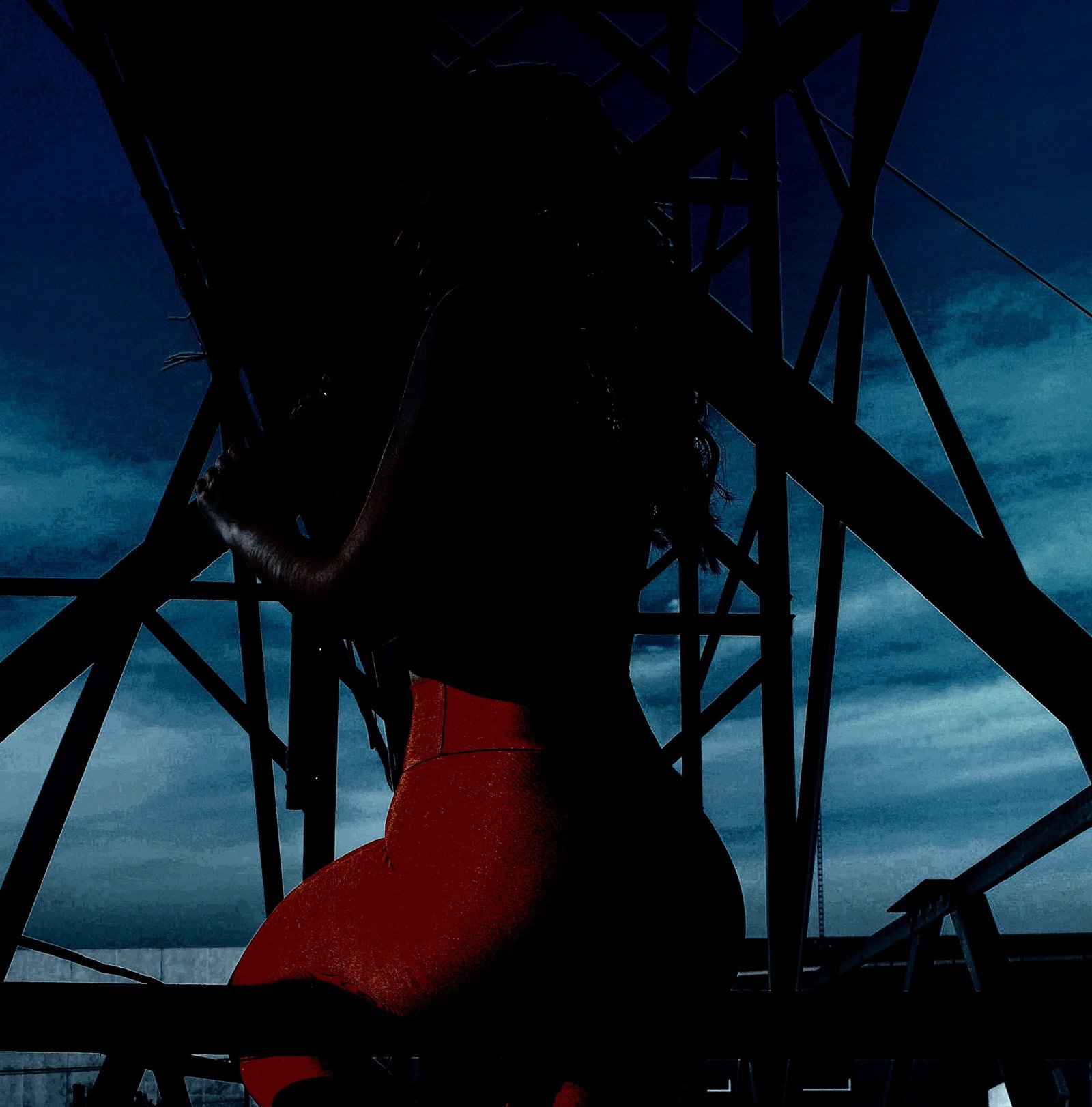 Silhouette of a woman in red pants standing among metal structures against a cloudy evening sky.