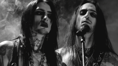 Gothic men singing on stage with long black hair and tattoos in a smoky atmosphere. Goth and Metal Are Not Phase.