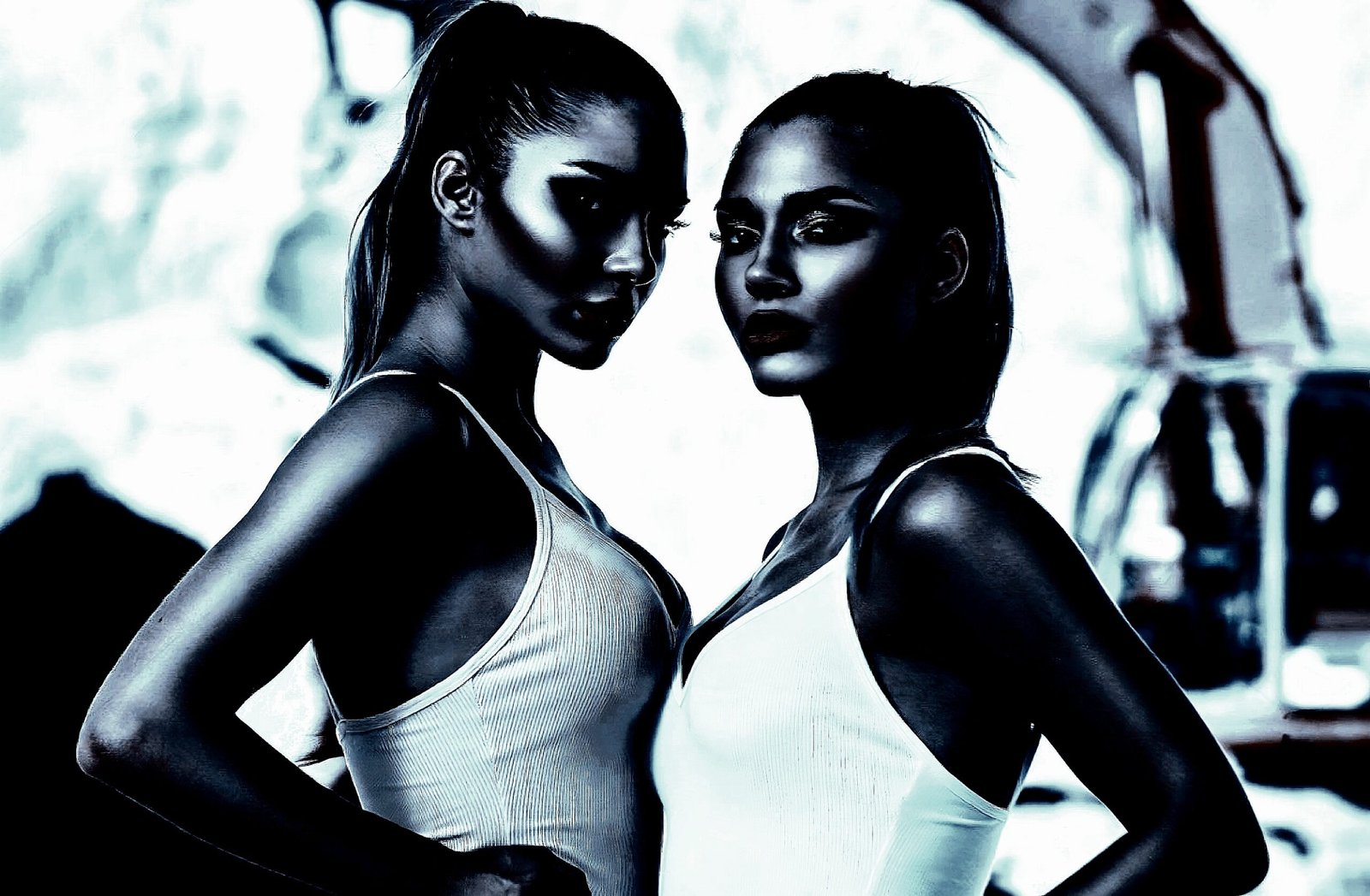 Two women standing face-to-face, exuding confidence and intensity in a dramatic setting.