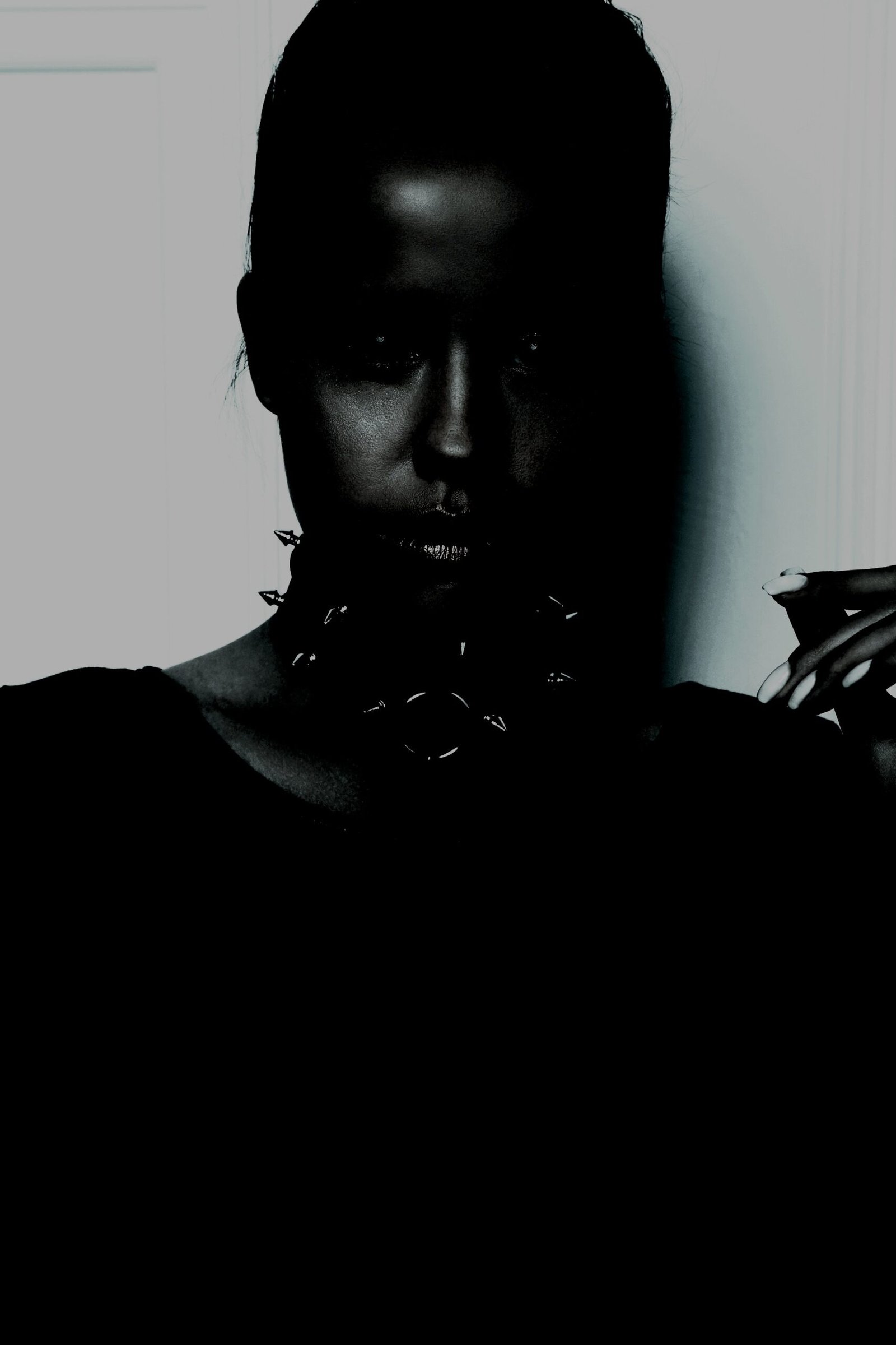 Close-up of a woman's face covered with dark gothic makeup and metal spikes, creating an intense and mysterious look.