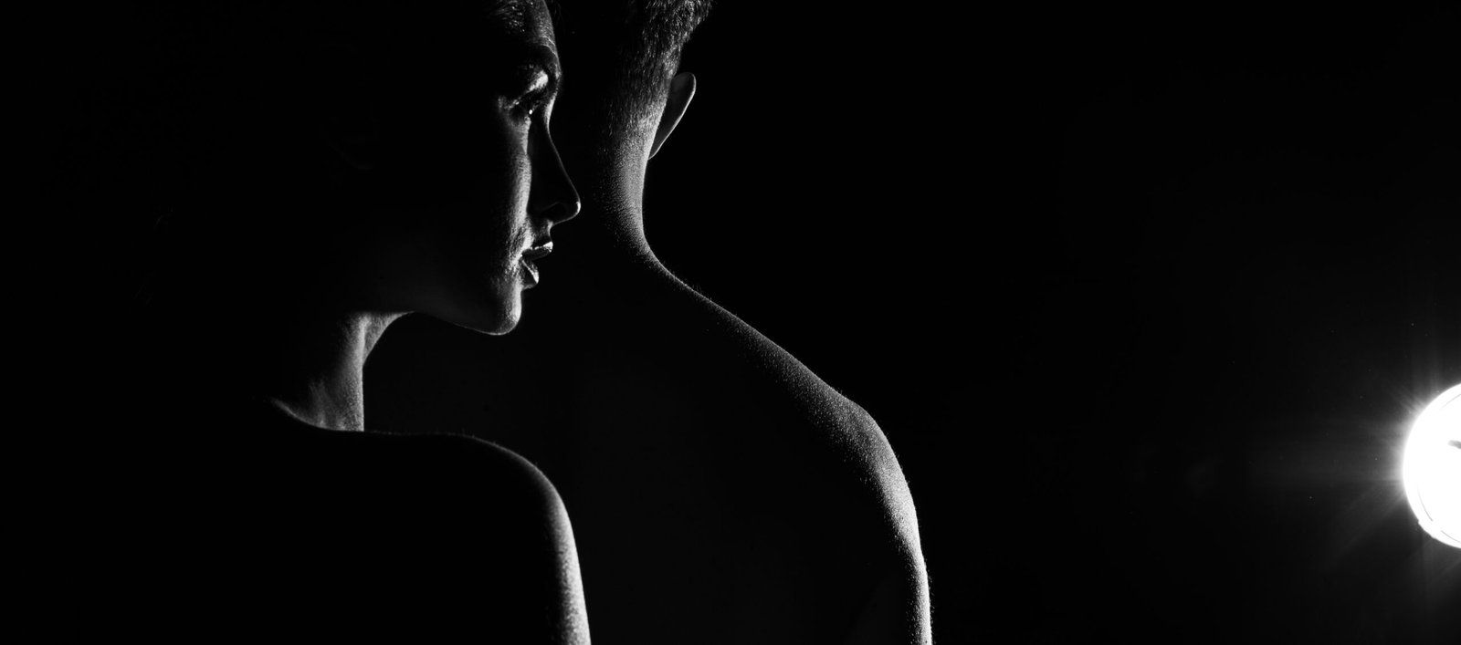 Silhouette of a couple in a dark room, emphasizing the intimacy and trust required in knife play.