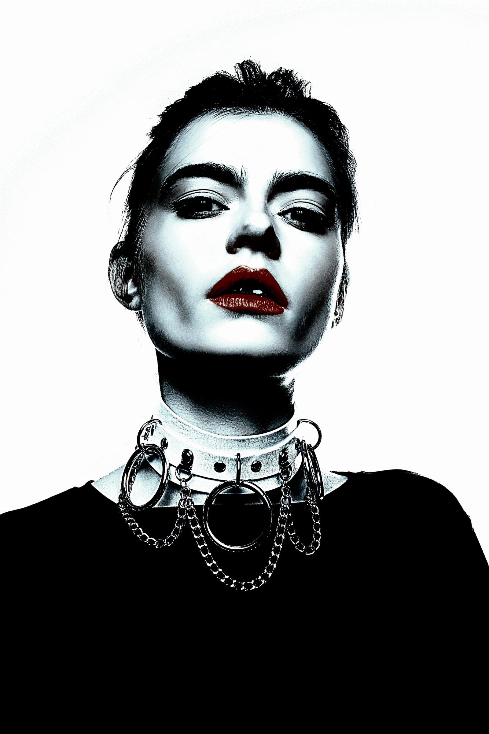 Portrait of a woman with bold Gothic jewelry featuring a multi-ring chain necklace.