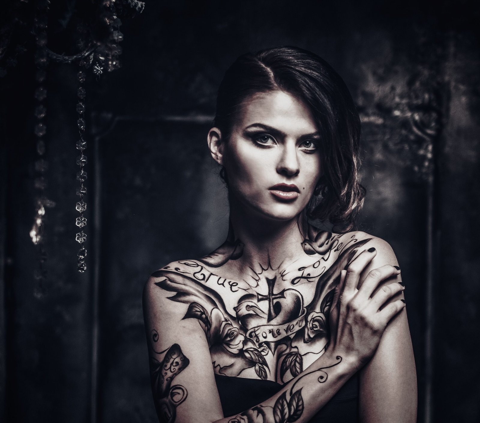Dark and moody portrait of a tattooed woman in a vintage setting, showcasing Tattoos in the Metal Subculture.