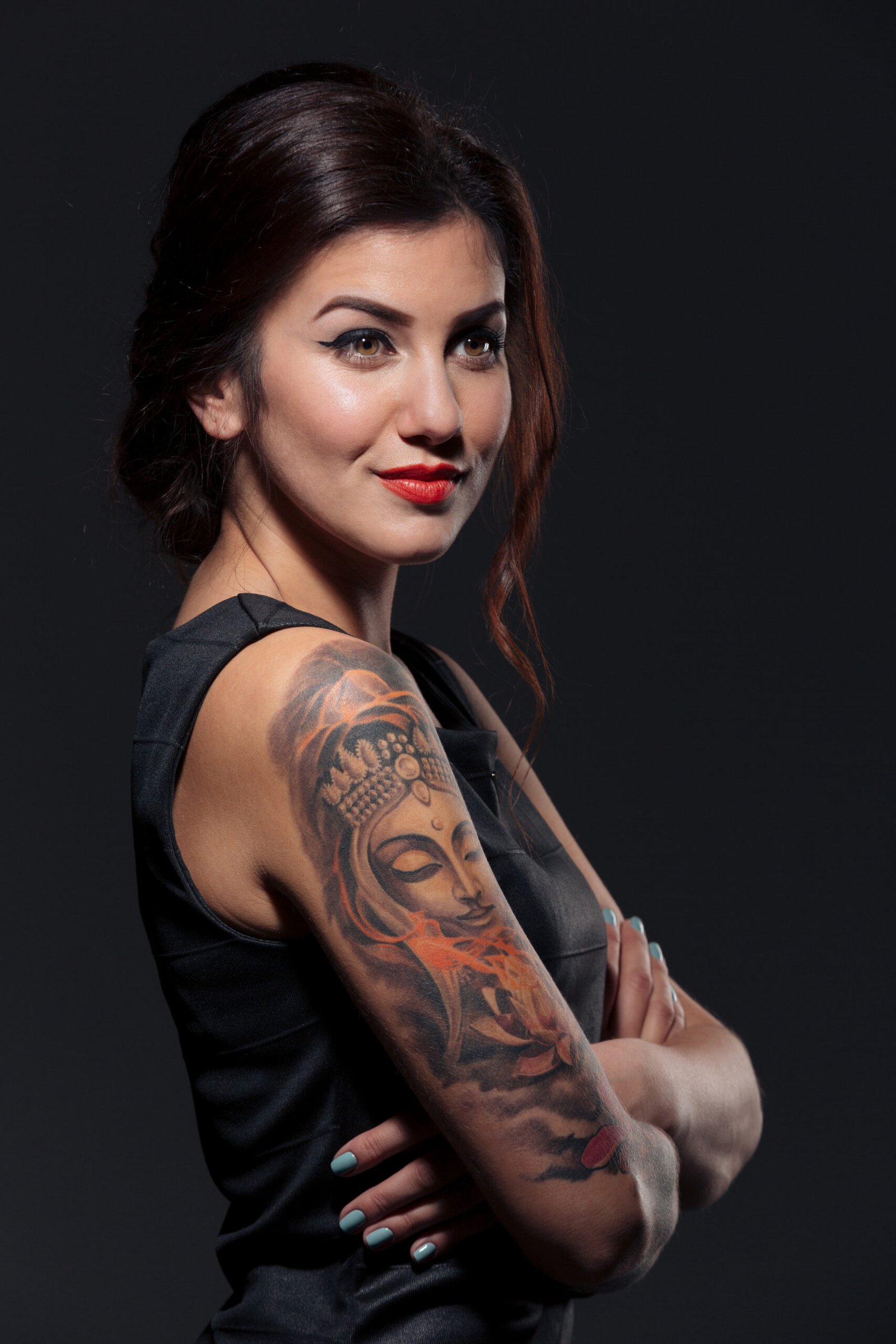 Woman with a serene Buddha tattoo on her arm, blending spirituality with Tattoos in the Metal Subculture.