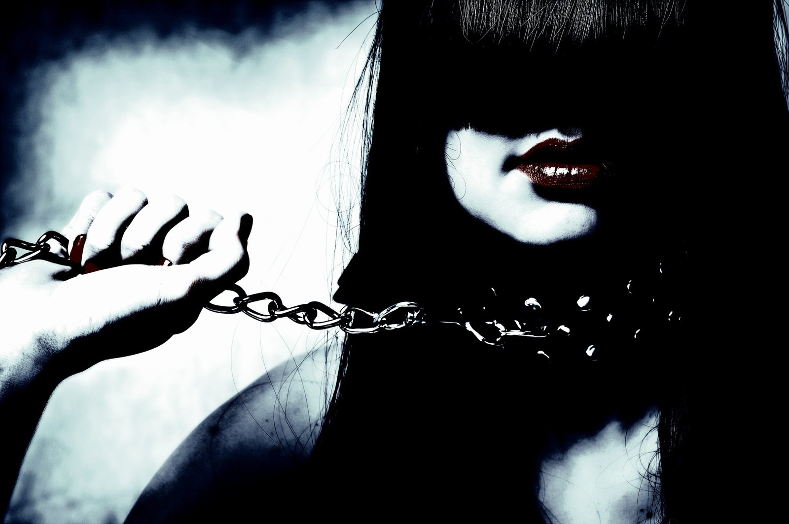 Woman in a stark, dramatic pose with hands bound by chains, reflecting the psychological dynamics of dominance and submission.