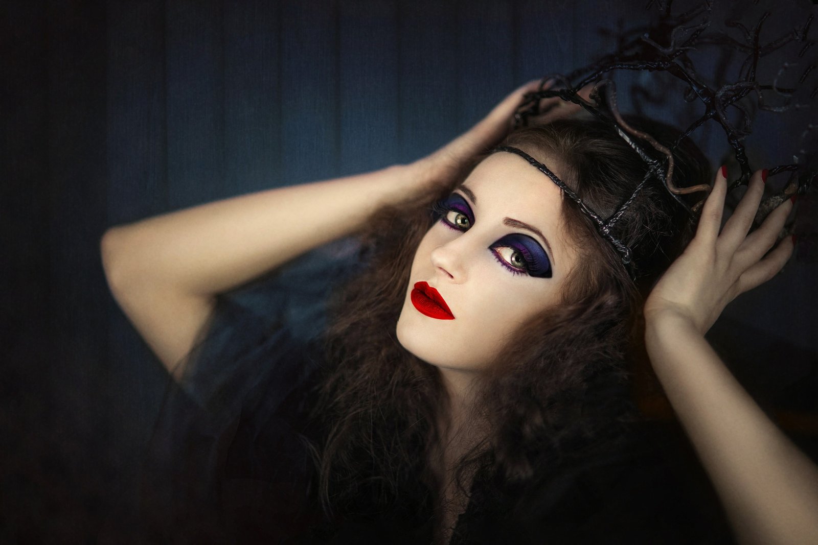Gothic woman with dramatic makeup and antler headpiece, portraying the sensation and eroticism of knife play.
