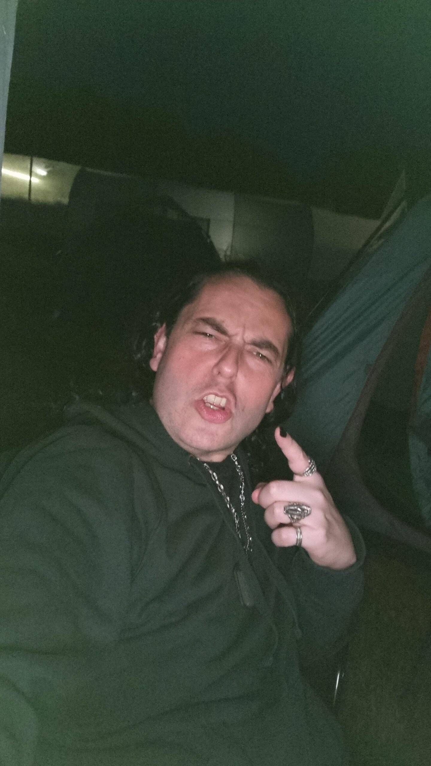 Man making a rock hand gesture and grimacing at Sweden Rock Festival 2024 campsite at night