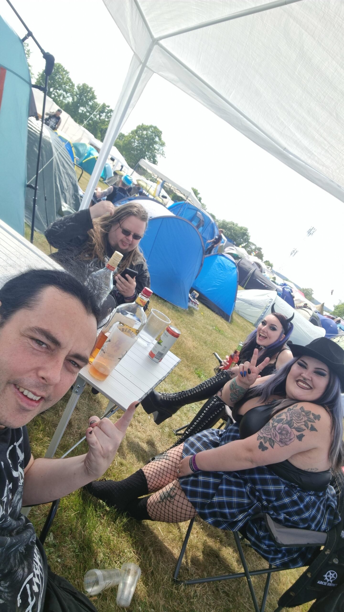 Group of friends smiling and posing with drinks at Sweden Rock Festival 2024 campsite