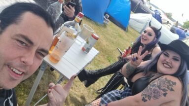 Group of friends enjoying drinks and making rock hand gestures at Sweden Rock Festival 2024 campsite