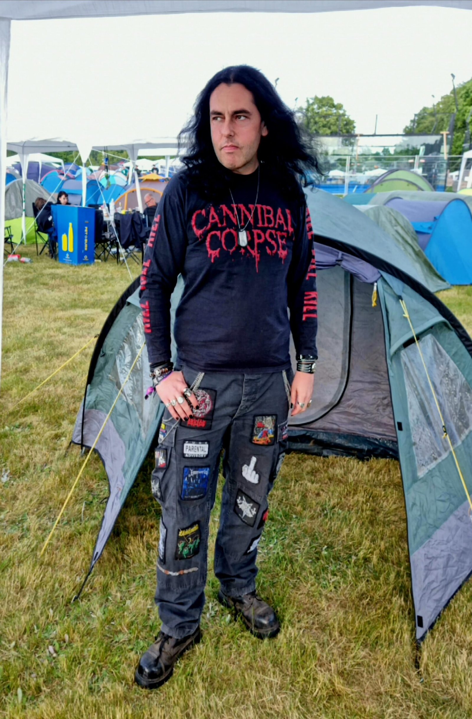 Man posing in a Cannibal Corpse shirt with patched pants at Sweden Rock Festival 2024 campsite