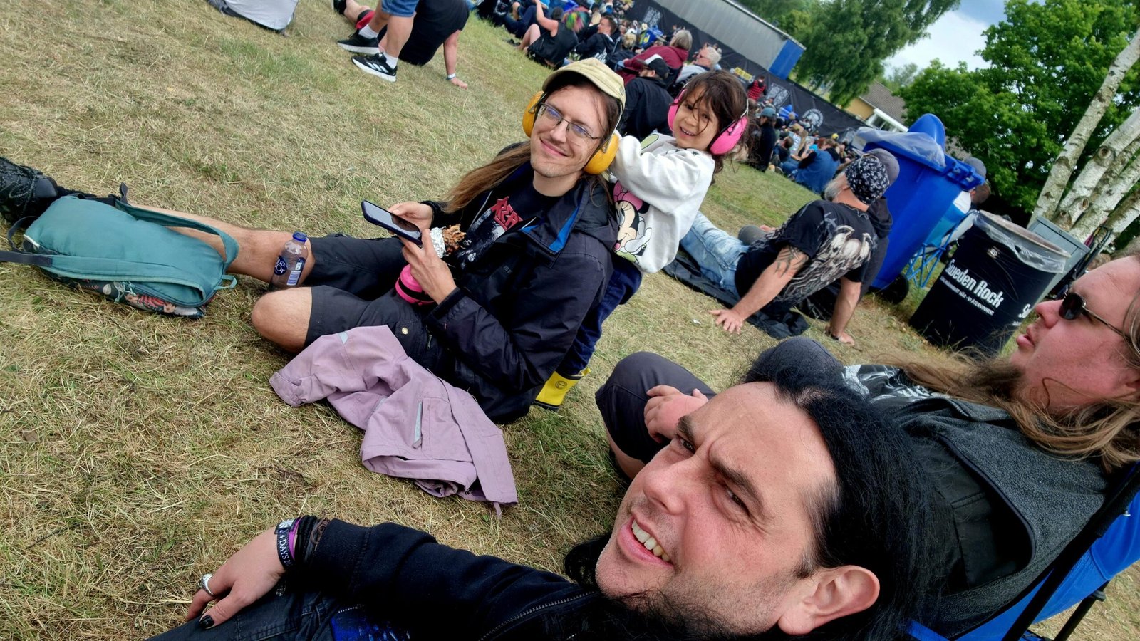 Friends sitting on the grass, enjoying the atmosphere at Sweden Rock Festival 2024