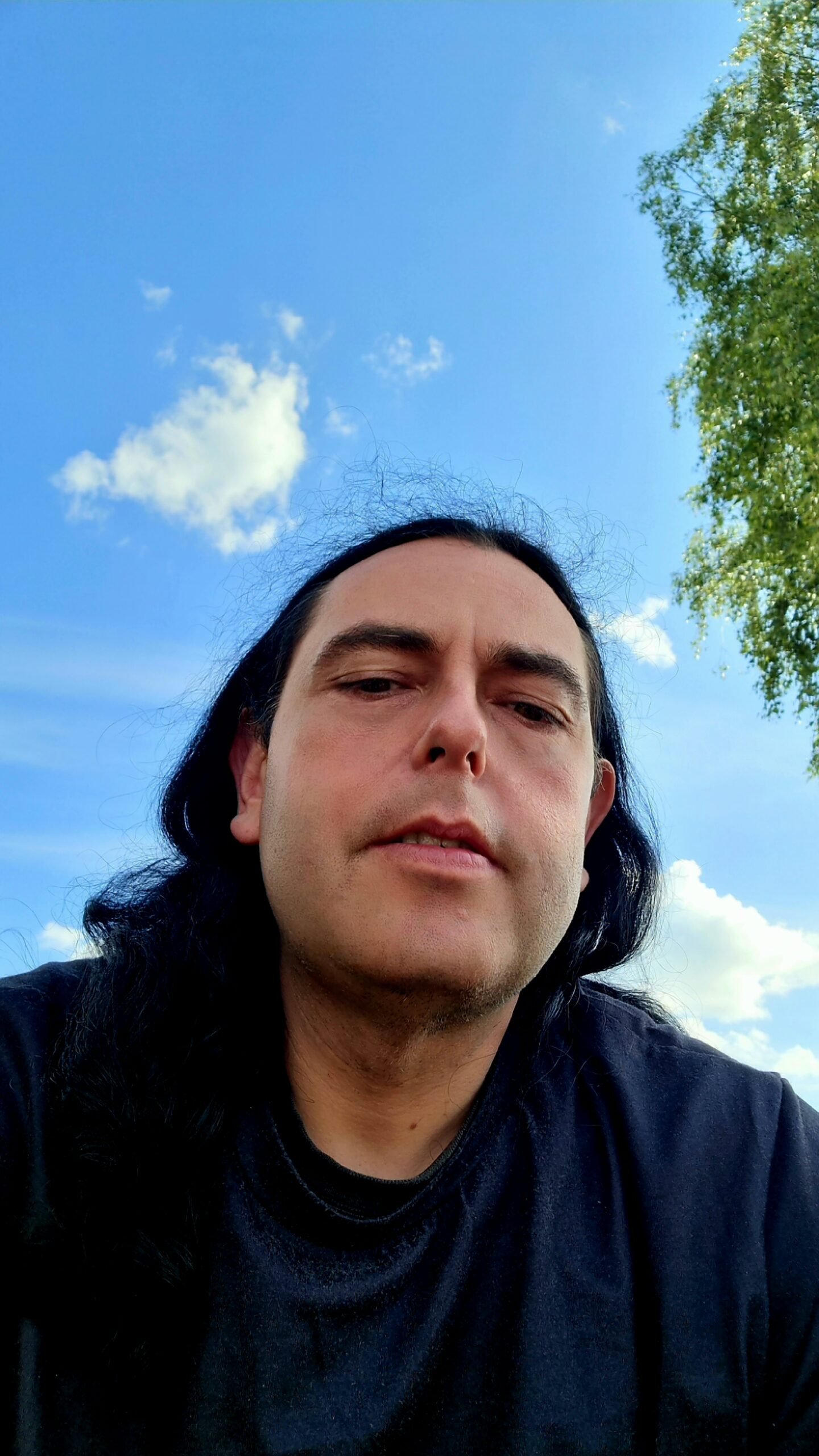 Man taking a selfie with a blue sky and clouds in the background at Sweden Rock Festival 2024