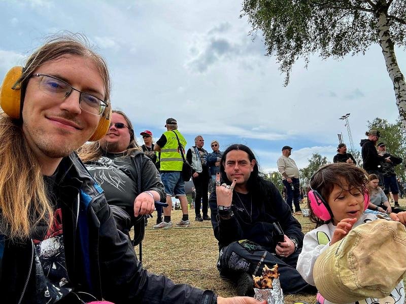 Group of friends wearing ear protection, sitting and enjoying the music at Sweden Rock Festival 2024