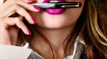Close-up of a sexy business woman with pink lipstick holding a pen