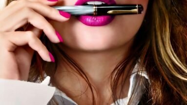 Close-up of a sexy business woman with pink lipstick holding a pen