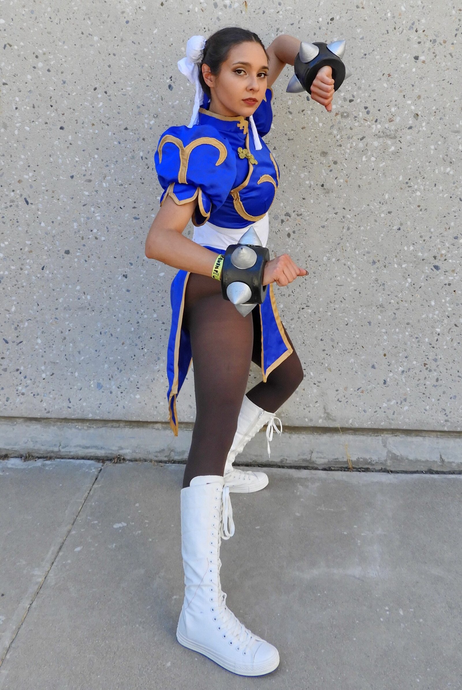 Cosplayer dressed as Chun-Li from Street Fighter, posing in a blue and gold costume with spiked wristbands.