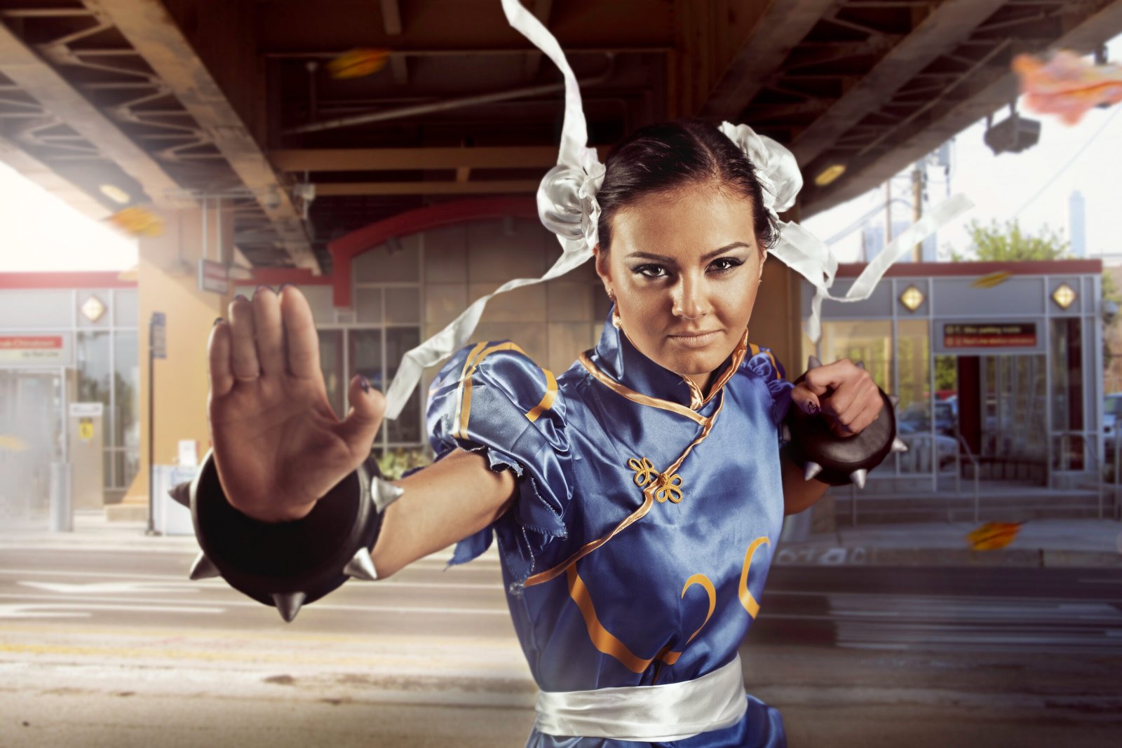Cosplayer dressed as Chun-Li from Street Fighter, striking a fighting pose under an urban overpass.