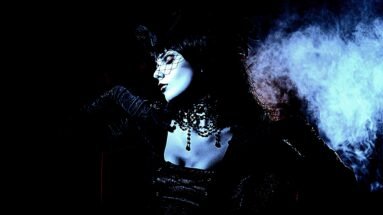 Gothic woman in a Witchy Fishnet Goth Mini Skirt Outfit with a veil and dark lighting