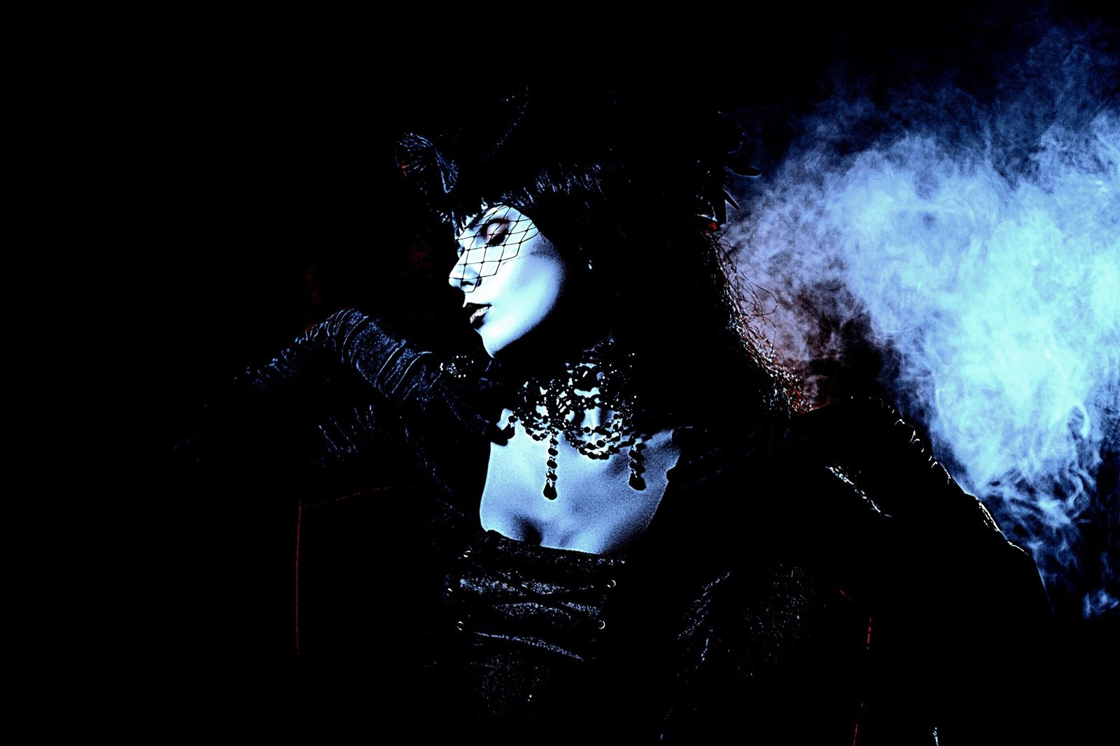 Gothic woman in a Witchy Fishnet Goth Mini Skirt Outfit with a veil and dark lighting