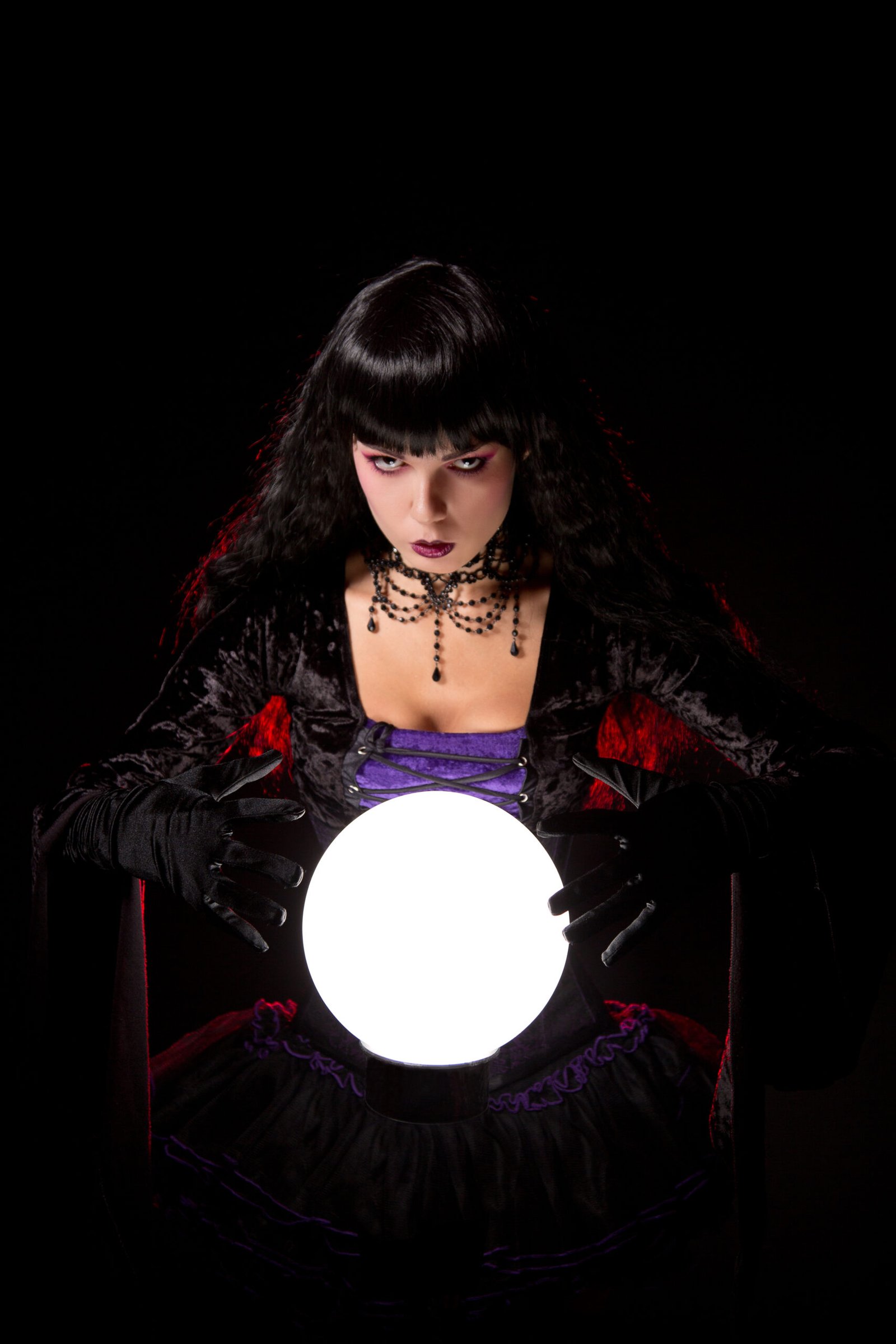Gothic woman in a Witchy Fishnet Goth Mini Skirt Outfit gazing into a glowing crystal ball