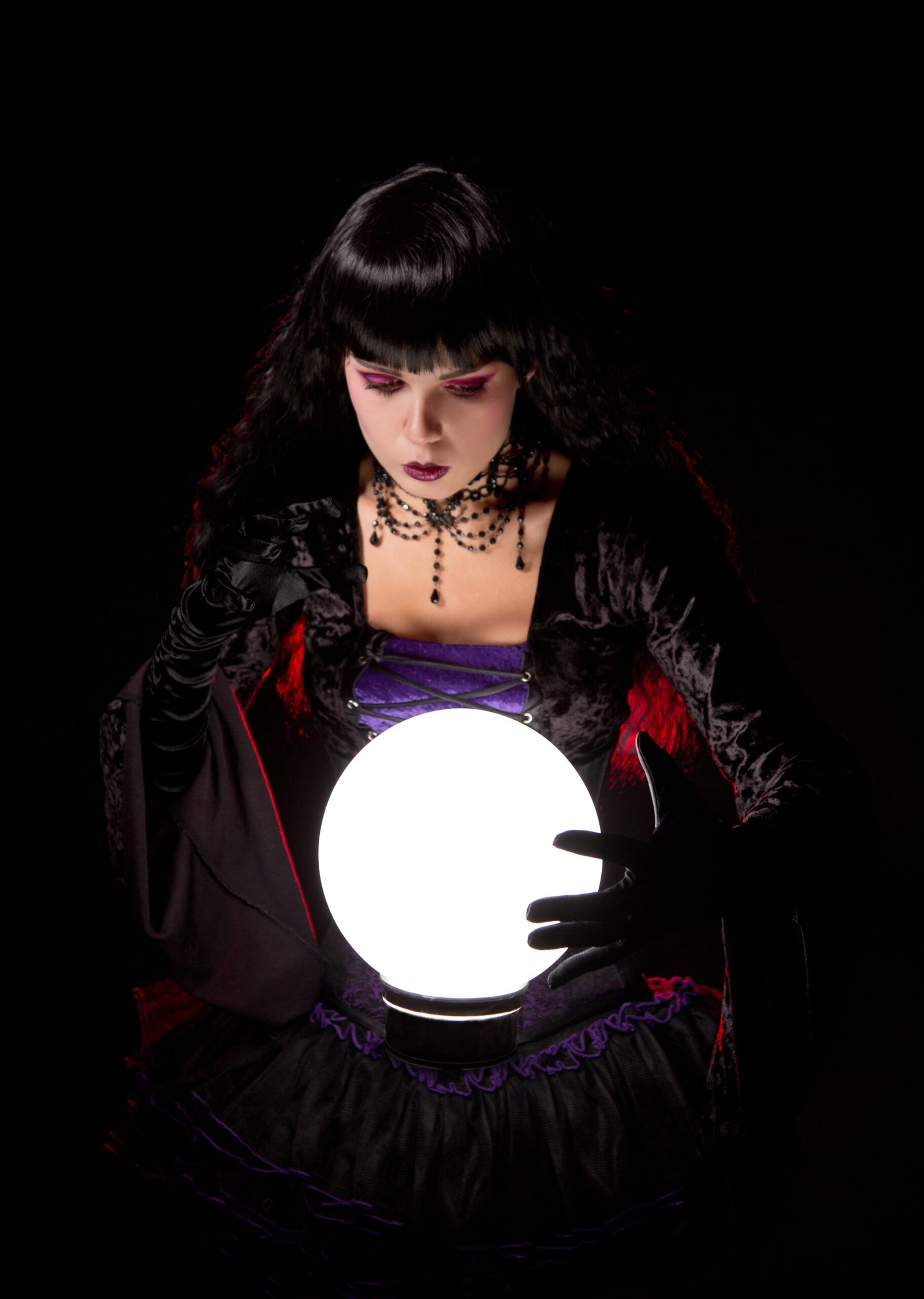 Gothic woman in a Witchy Fishnet Goth Mini Skirt Outfit holding a glowing crystal ball
