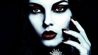 Gothic jewelry featuring an intricate snowflake gem necklace on a woman with striking makeup and dark red nails.