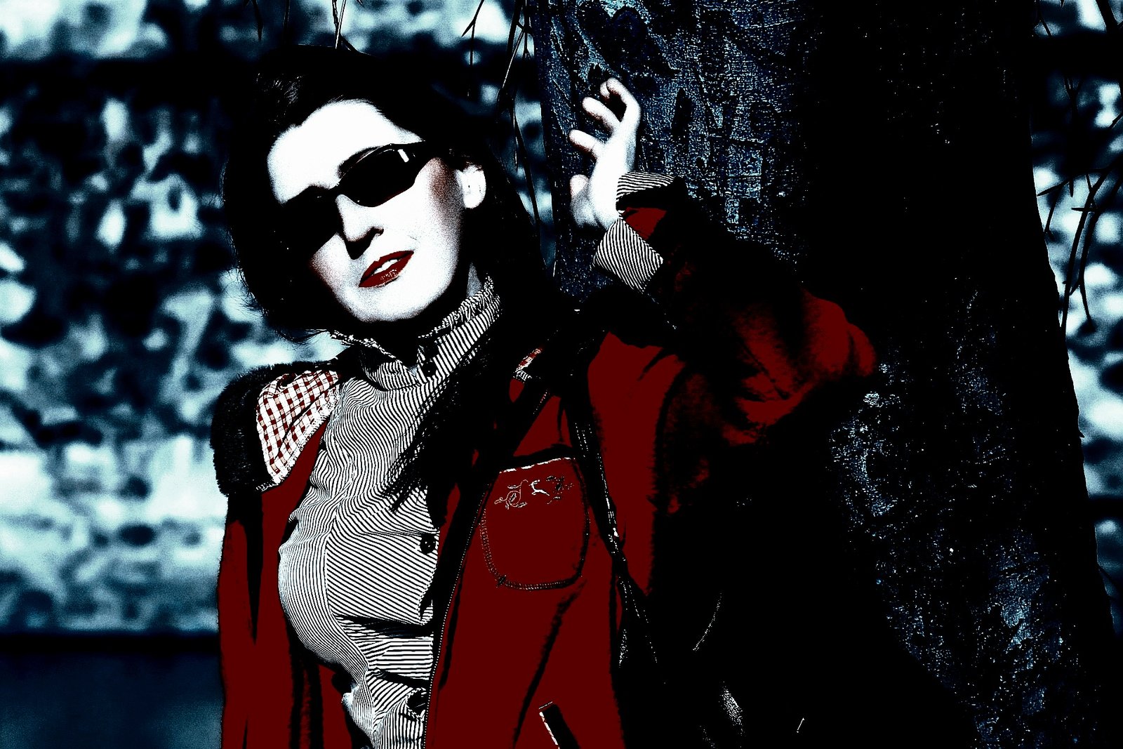Edgy woman in sunglasses and a unique outfit, standing in front of a retro vehicle with a playful expression.
