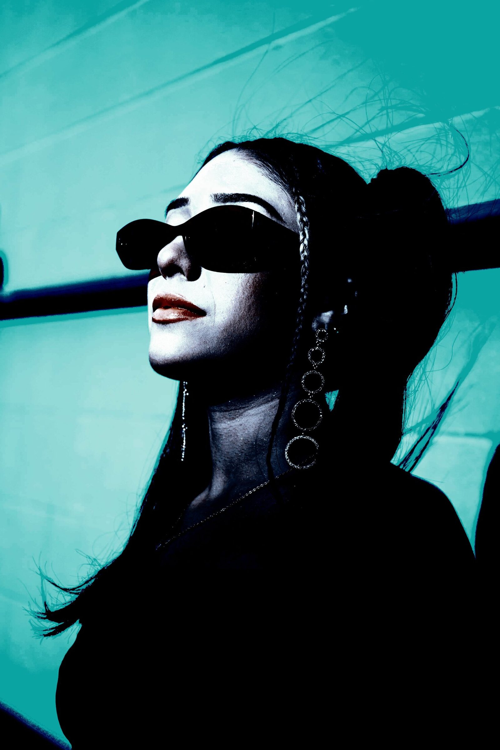 Stylish woman with red-tinted round sunglasses and a layered pearl necklace against a dark background.