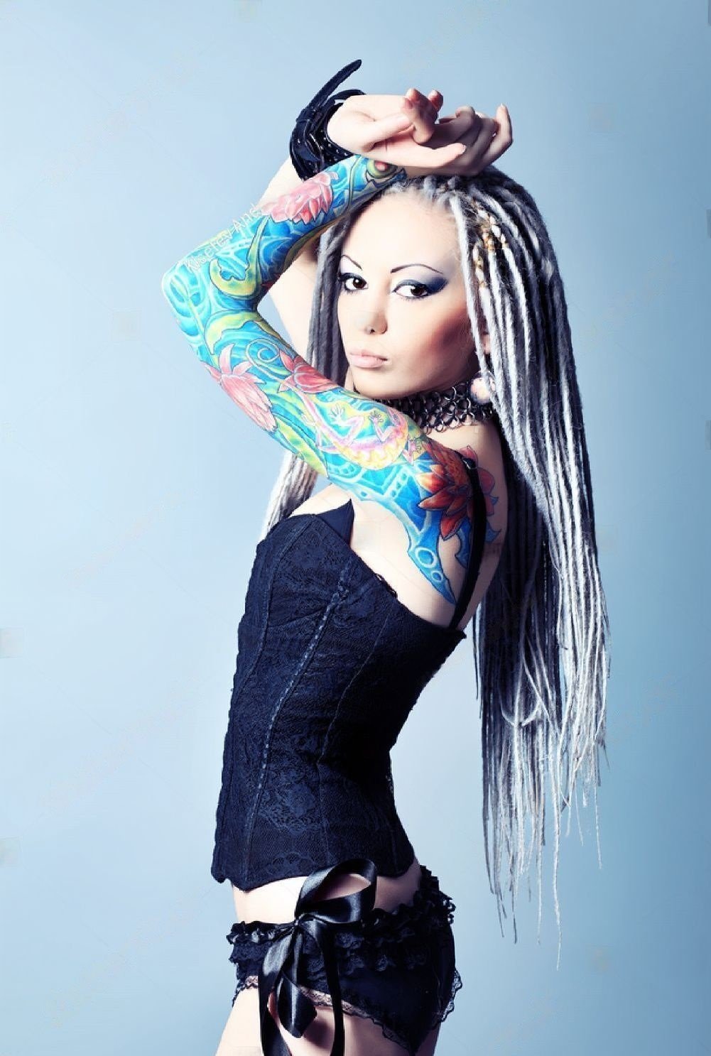 Stylish young woman with white dreadlocks and colorful full sleeve tattoo, posing in black lingerie.