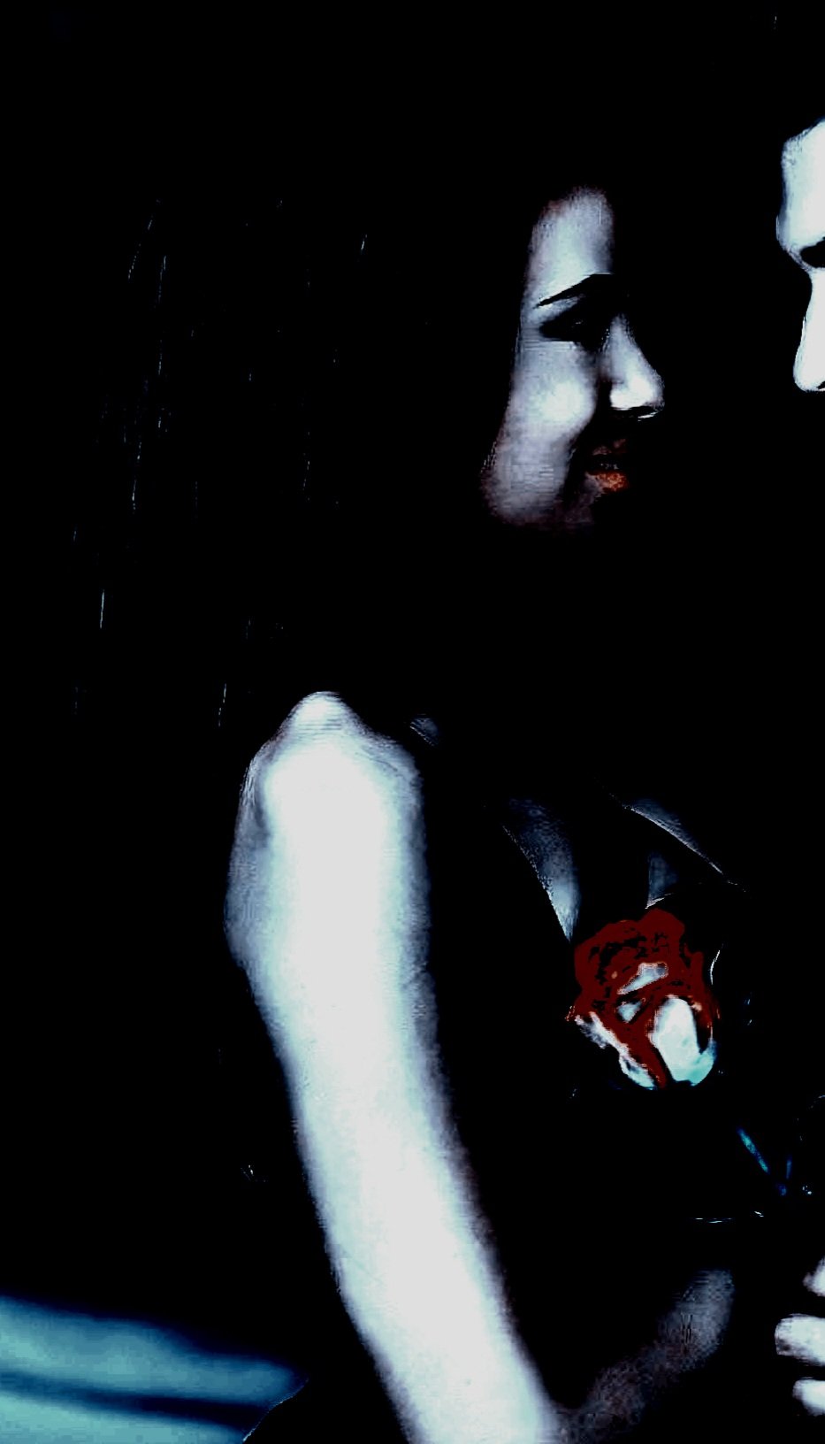 A silhouetted woman sitting on a couch, holding an object close to her face, bathed in moody lighting.