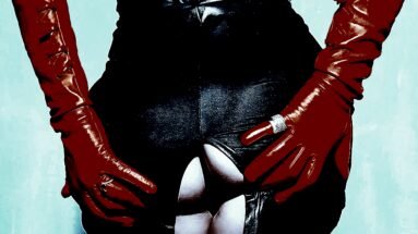 Scat Play: Close-up of a person wearing tight black latex pants and red gloves, with the pants unzipped to reveal bare skin.